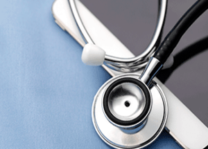 A stethoscope resting on top of a smartphone, both placed on a light blue surface.