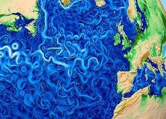 A colorful map shows swirling patterns in the Atlantic Ocean, representing ocean currents between North America, Europe, and Africa. Land areas are shaded green and tan, while the ocean is depicted in vibrant blues and whites.