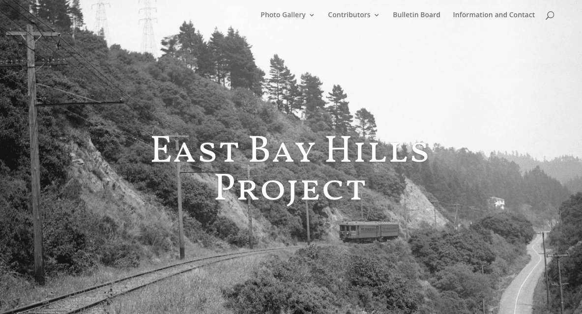 Black-and-white photo of a train on railroad tracks curving through hilly, wooded terrain; large white text reads East Bay Hills Project over the image.
