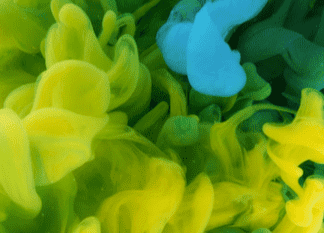 Swirling clouds of vibrant yellow and blue ink underwater create soft, abstract shapes against a dark background.
