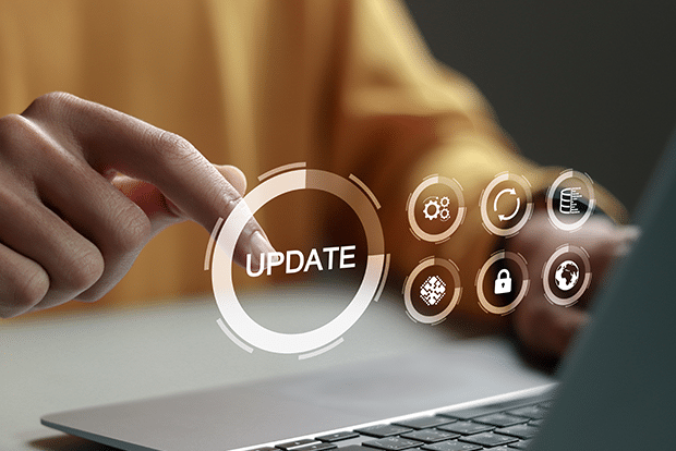 A person’s hand pointing toward a virtual “UPDATE” button on a laptop, surrounded by digital security and settings icons, symbolizing software update or system upgrade.