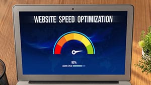 A laptop screen displays a gauge labeled Website Speed Optimization with the needle in the green zone and a loading speed of 90%. A plant and notebook are visible beside the laptop.